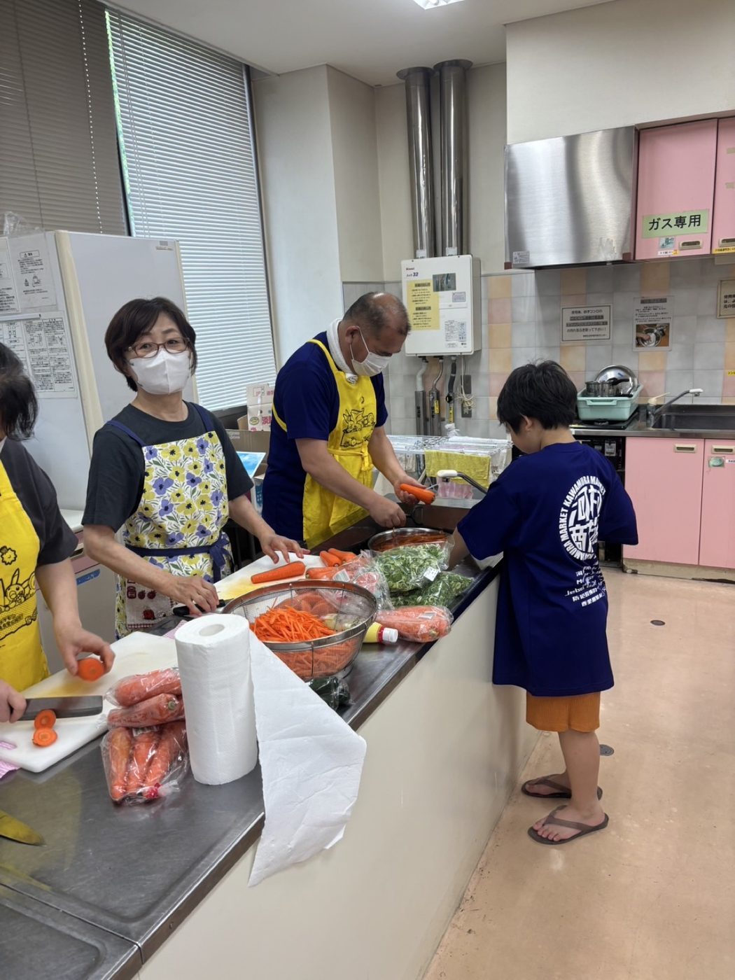 ボランティアと子どもが一緒ににんじんを切っている様子